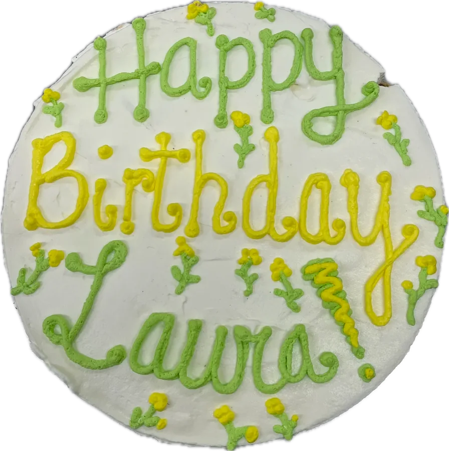 Round ice cream cake piped with “Happy Birthday Laura” in yellow and green