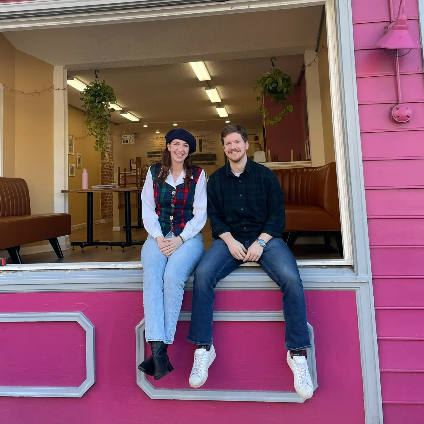 Erin and Connor sitting on the pink window ledge of the shop