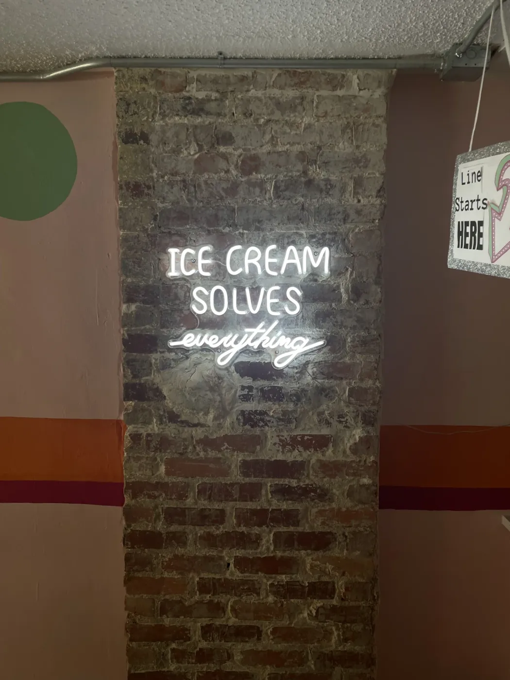 A neon sign on the brick wall inside Bev’s reads “Ice cream solves everything”