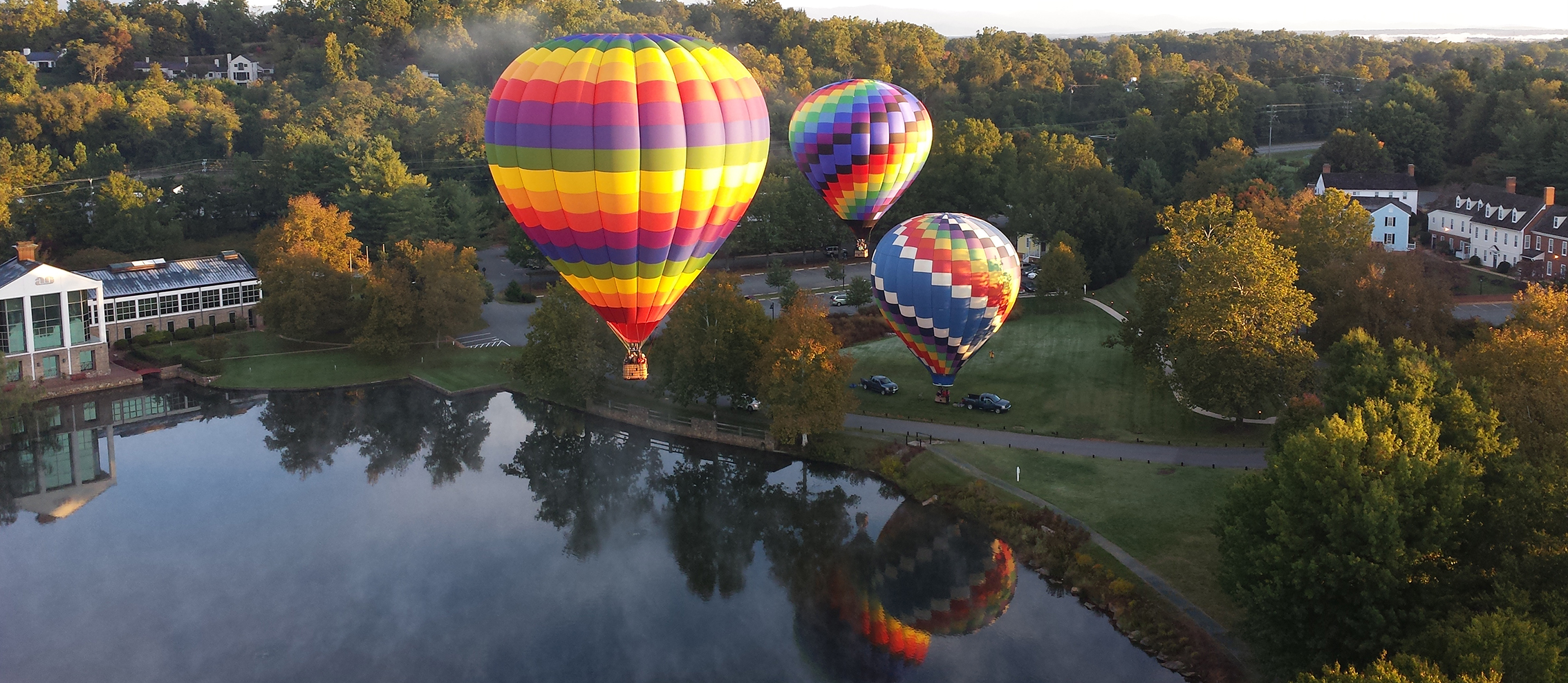 Colorful hot air balloons above a lake and Virginia countryside