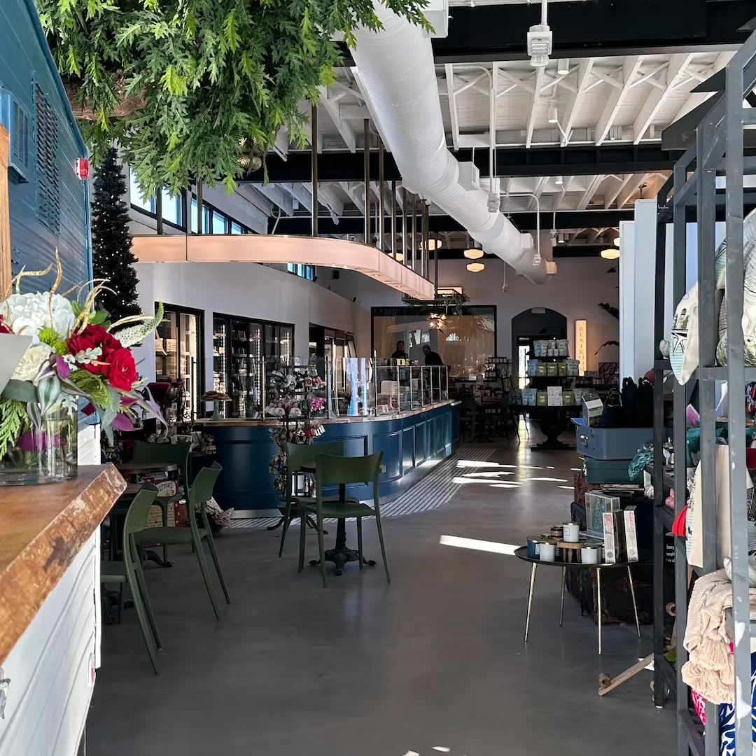 Inside Shyndigz Market: a long counter, green chairs, hanging plants, and a bright gift shop