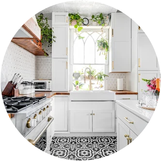 A white kitchen with a farmhouse sink, arched window, and black-and-white tile floor