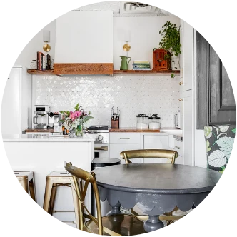 A dining nook with gold chairs beside a white-tiled kitchen