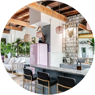 A kitchen with a pink retro fridge, exposed beams, and black bar stools